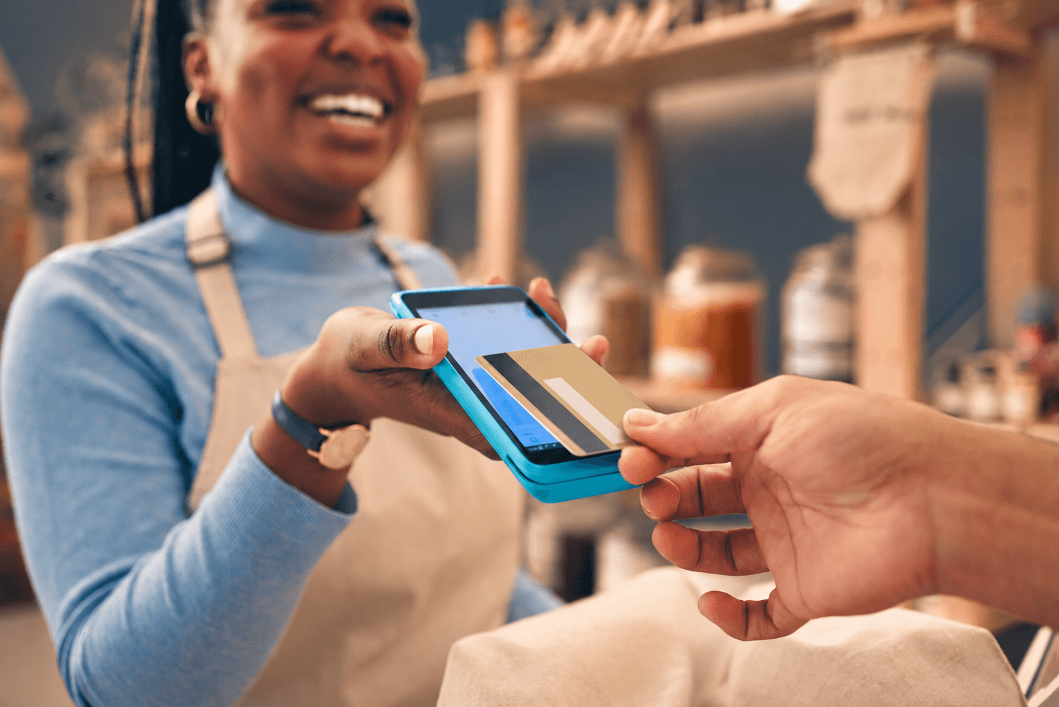 A shop owner holding out a phone while a customer taps a card against it